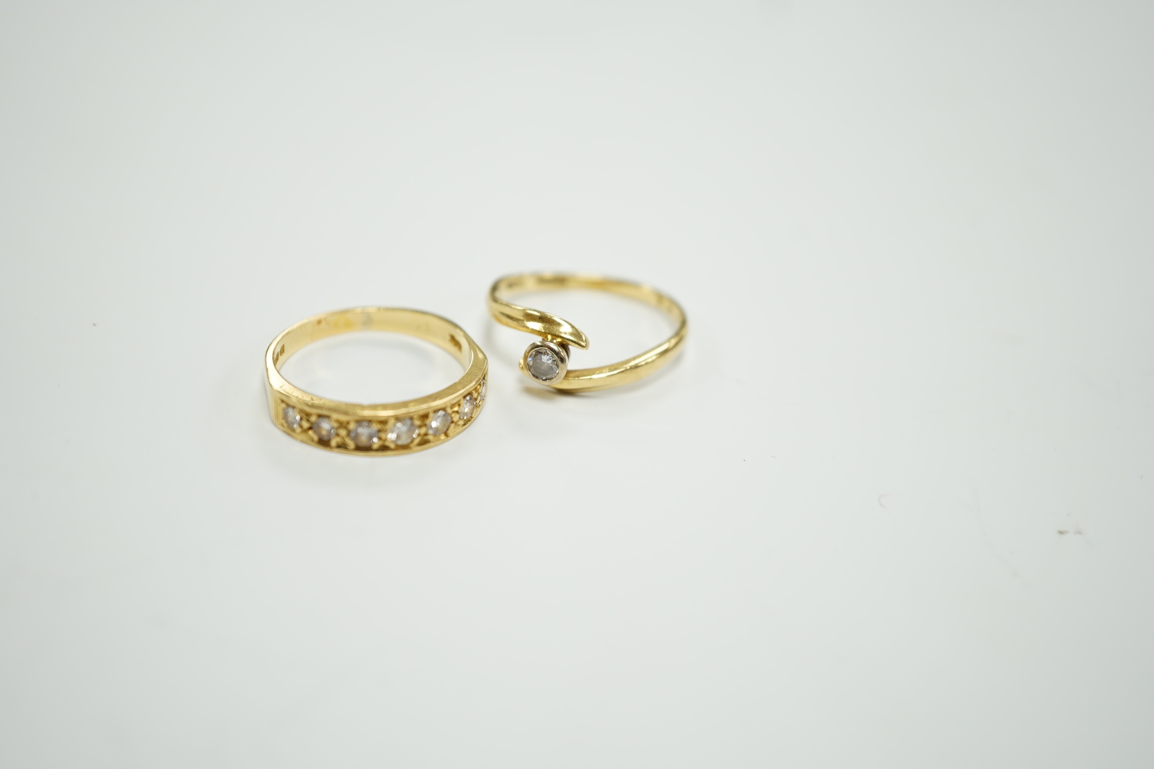 A modern 18ct gold and graduated seven stone diamond set half hoop ring, size O and a similar solitaire diamond ring with crossover setting, gross weight 6.4 grams.